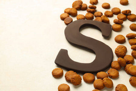 Sinterklaas (Saint Nicholas) Day. Chocolate letter S and kruidnoten cookies on light background, closeup. Space for textの写真素材