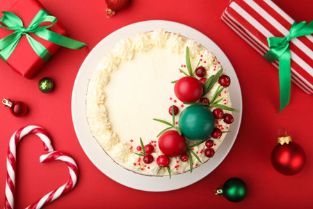 Delicious sponge cake with Christmas decor and berries on red background, flat layの写真素材