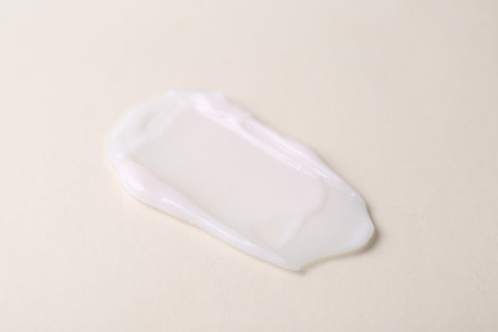 Sample of moisturizing cream on beige background, closeup