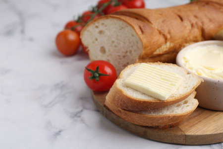 Cut baguette with butter and tomatoes on white marble table, closeupの写真素材