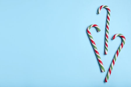 Candy canes on light blue background, flat lay with space for text. Christmas treatの写真素材