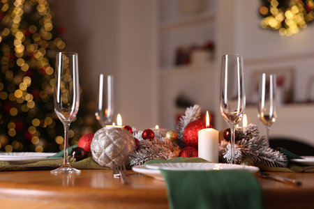 Stylish Christmas table setting with plates, glasses and burning candles in festive decorated room, closeup. Bokeh effectの写真素材