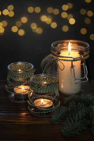 Christmas lanterns and festive decor on wooden table against dark background with blurred lights,...