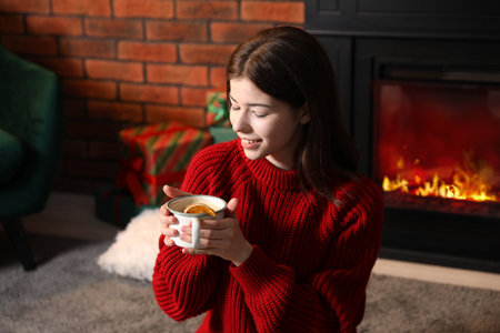 Beautiful woman with cup of tasty cocoa enjoying Christmas season at homeの写真素材