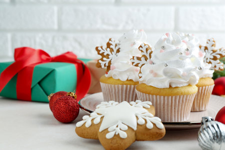 Tasty cupcakes with Christmas decor and gingerbread cookies on white table, closeup. Space for textの写真素材