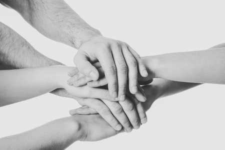 Young people putting their hands together on white background, closeup. Black and white toningの写真素材