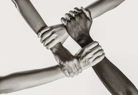 Group of multiracial people joining hands together, closeup. Black and white toning