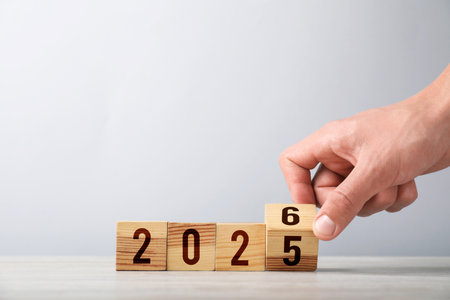 Man flipping cube with numbers 5 and 6 to make 2026 at table, closeup