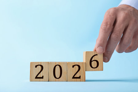 Man putting cube with number 6 on light blue background, closeup