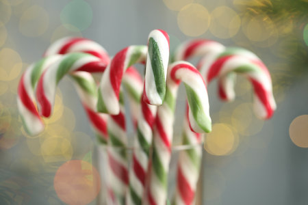 Many candy canes in glass on blurred background, closeup with bokeh effect. Christmas treatの写真素材