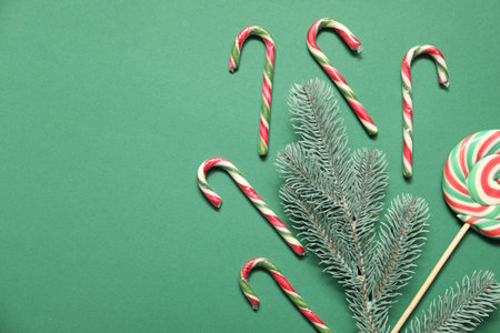 Christmas composition with candy canes, lollipop and decor on green background, flat lay. Space for...