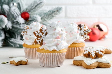 Tasty cupcakes with Christmas decor and gingerbread cookies on white table, closeupの写真素材