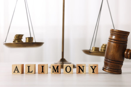 Alimony word made of cubes with letters, judge's gavel and scales of justice with coins on tableの写真素材