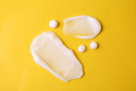 Samples of moisturizing creams on yellow background, flat layの写真素材
