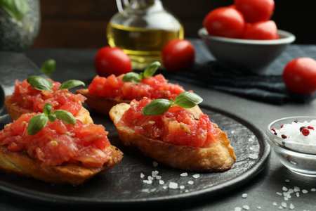 Tasty bruschettas with tomatoes and basil served on black table, closeupの写真素材
