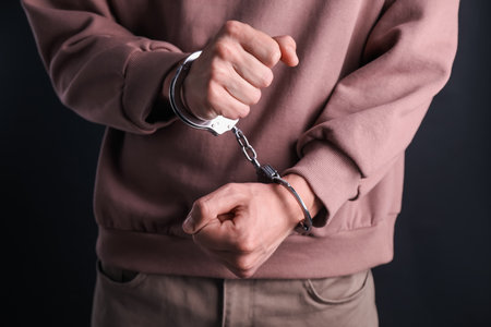 Man in handcuffs on black background, closeup