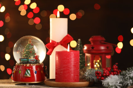 Burning candles and Christmas decor on wooden table against dark background with blurred lights, closeup. Bokeh effectの写真素材