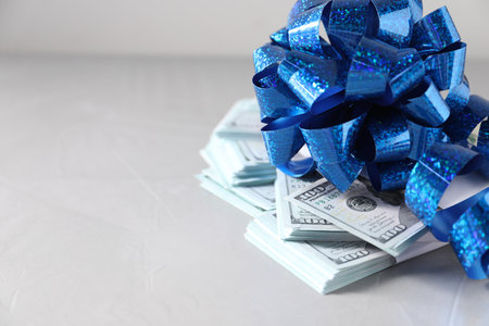 Dollar banknotes with bow on light background, closeup. Space for textの写真素材