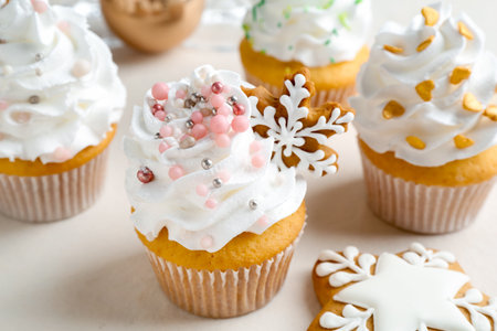 Tasty cupcakes with Christmas decor and gingerbread cookies on white table, closeupの写真素材