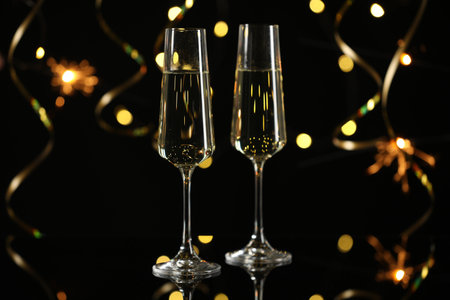 Happy New Year. Sparkling wine in flute glasses against sparklers and blurred lights on black background, bokeh effectの写真素材