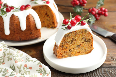 Slice of tasty Christmas cake with cranberries served on wooden table, closeup