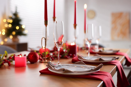 Stylish Christmas table setting with plates, glasses and burning candles in room, closeup. Bokeh effectの写真素材