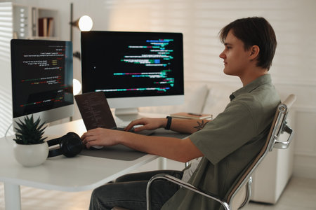 Programmer working on computer and laptop at white table in officeの写真素材