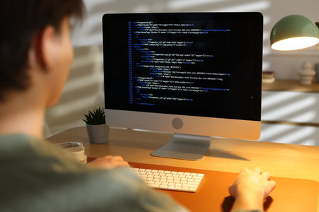 Programmer working on computer at table in officeの写真素材