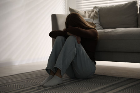 Depressed teenage girl near sofa at homeの写真素材