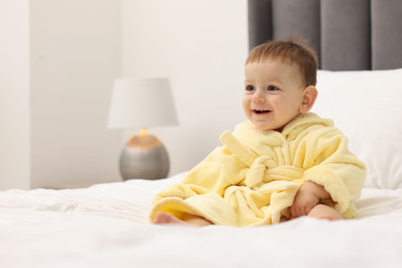 Cute baby in bathrobe on bed at homeの写真素材