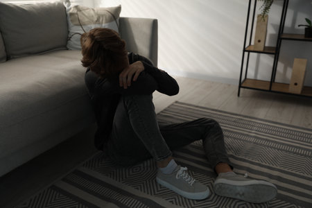 Depressed teenage boy near sofa at homeの写真素材