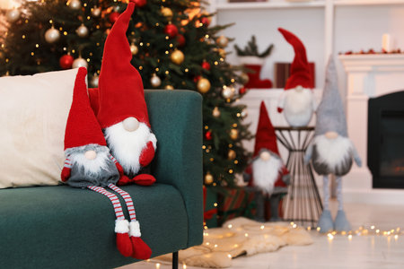 Funny Christmas gnomes on sofa in decorated room, space for textの写真素材