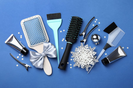 Different hairdresser's tools and Christmas decor on blue background, flat lay