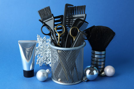 Different hairdresser's tools and Christmas decor on blue background, closeup