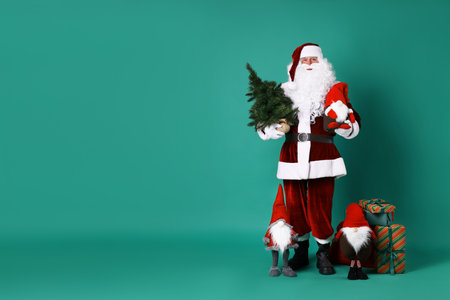 Santa Claus with Christmas gifts and festive decor on green background, space for textの写真素材
