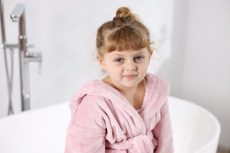 Cute girl in bathrobe near bathtub at homeの写真素材