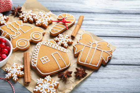 Tasty gingerbread cookies and spices on gray wooden background, closeup. Christmas treat