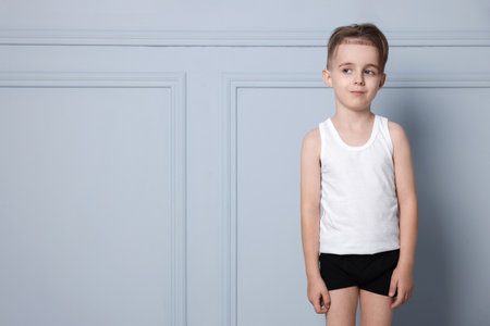 Little boy in underwear near light wall. Space for text