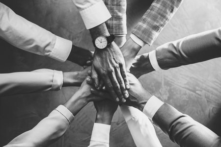 People holding hands together over stone background, top view. Black and white toning. Unity conceptの写真素材