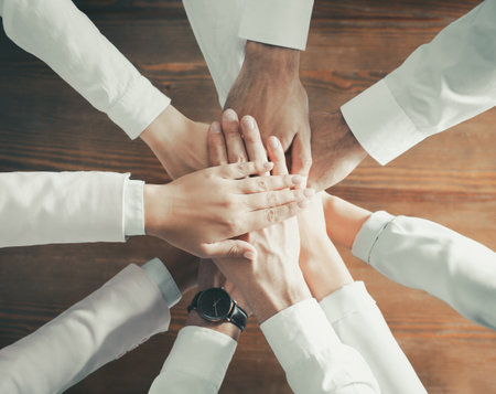 People holding hands together over wooden background, top view. Unity conceptの写真素材