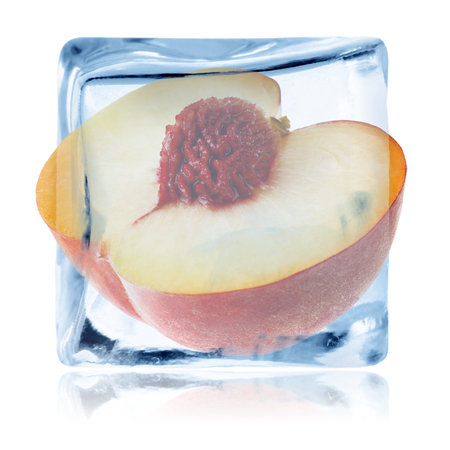 Half of peach in ice cube isolated on whiteの写真素材