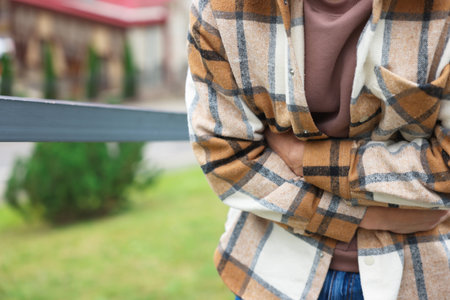 Young man suffering from stomachache and nausea outdoors, closeup. Space for textの写真素材