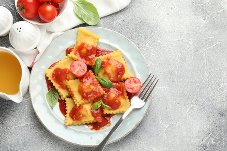 Delicious ravioli with tomato sauce and basil served on gray table, flat lay. Space for textの写真素材
