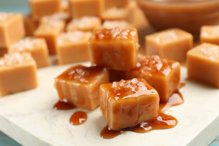Tasty candies with salt and caramel sauce on light blue table, closeupの写真素材