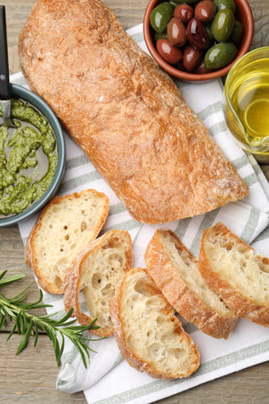 Cut ciabatta, spices and olives on wooden table, flat layの写真素材