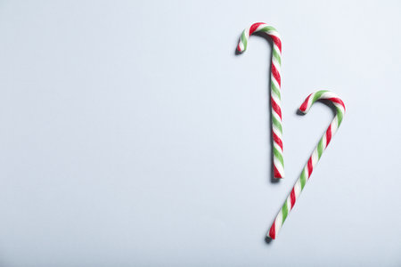Tasty candy canes on gray background, flat lay with space for text. Christmas treatの写真素材