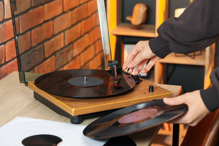 Woman turning record player with vinyl disk on at home, closeupの写真素材