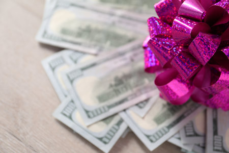 Dollar banknotes with bow on light wooden background, closeupの写真素材