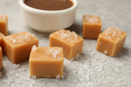 Tasty candies with salt and caramel sauce on gray textured table, closeupの写真素材
