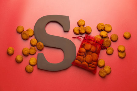 Saint Nicholas (Sinterklaas) day. Chocolate letter S and kruidnoten cookies on red background, flat layの写真素材
